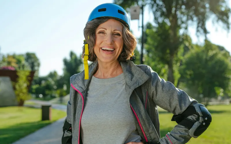 Smiling older woman in a bike helmet outdoors