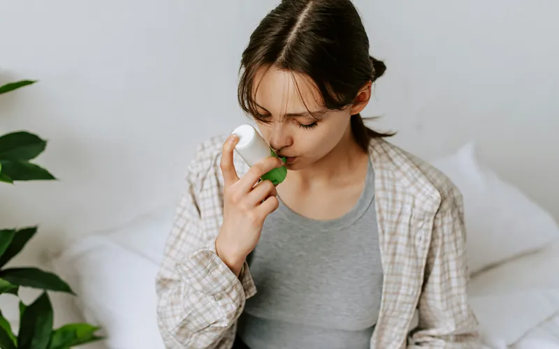 Woman using an asthma inhaler at home