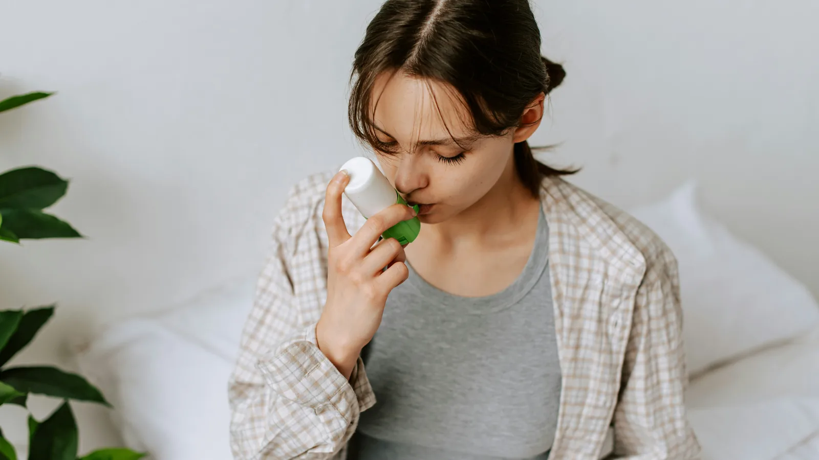 Woman using an asthma inhaler at home