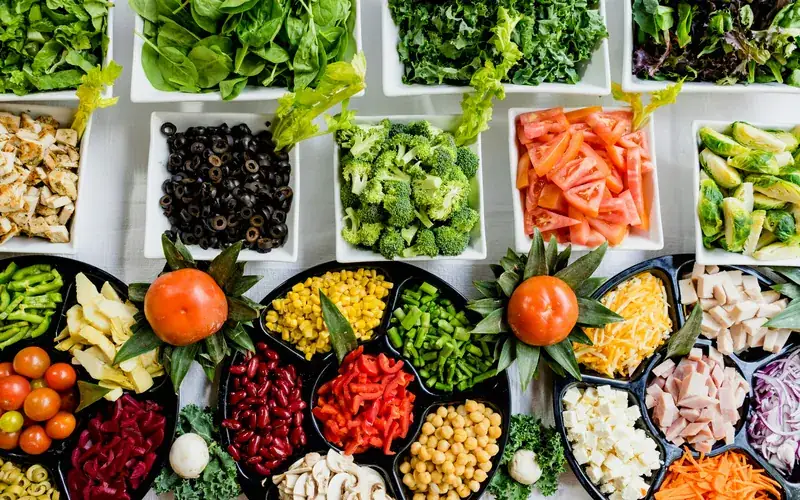 Bowls of fresh vegetables, beans and greens laid out on a table