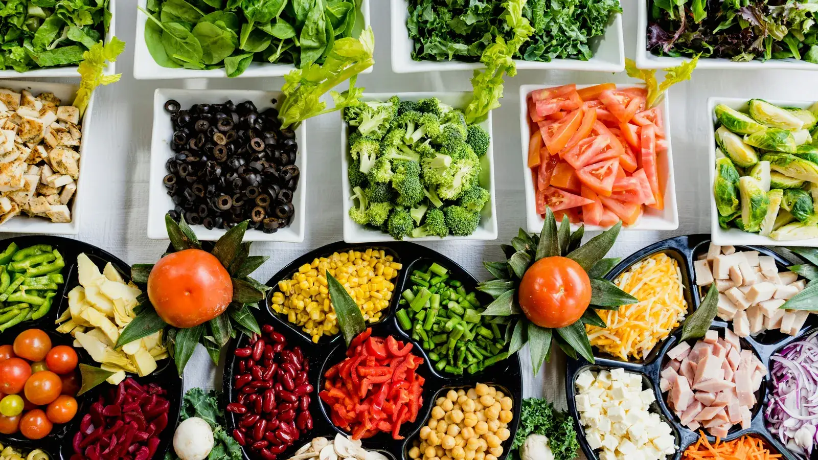 Bowls of fresh vegetables, beans and greens laid out on a table