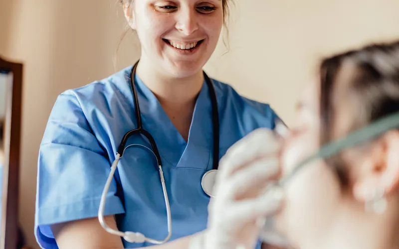 A nurse with a stethoscope smiling while talking with a patient