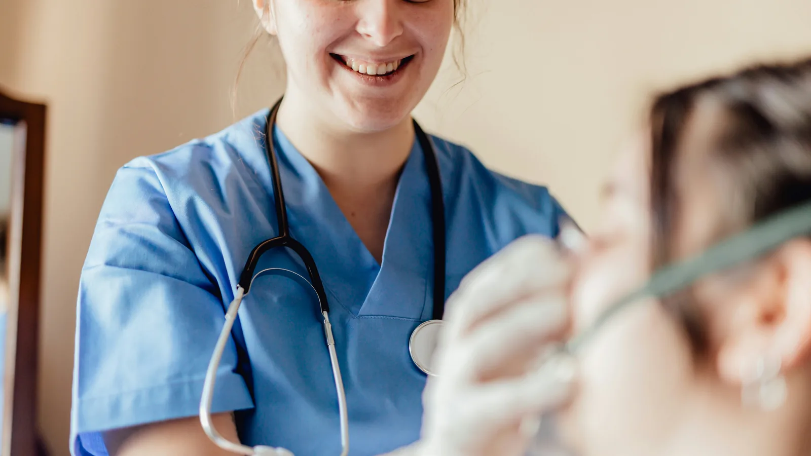 A nurse with a stethoscope smiling while talking with a patient